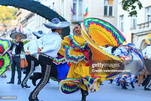 darsteller aus mexikanischen gruppe in traditionellen kostümen tanzen auf der straße - latino festival stock-fotos und bilder