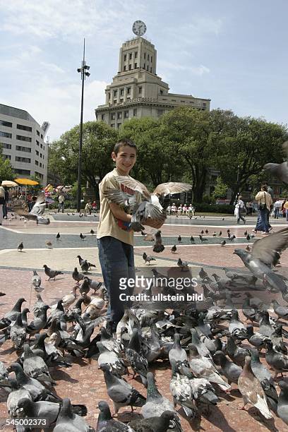 Spain - Barcelona: Plaza de Catalunya, boy is feeding doves