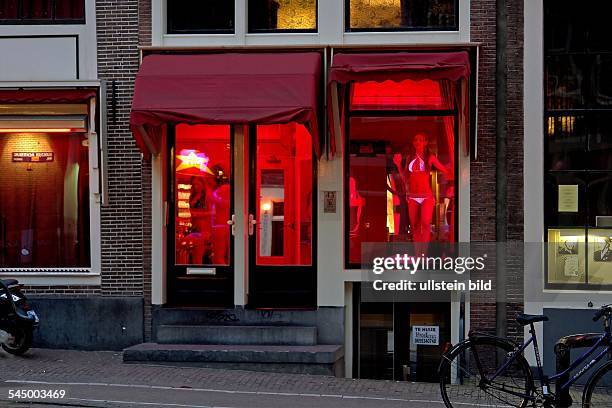 Netherlands - Amsterdam: red light district at night, prostitute at the window