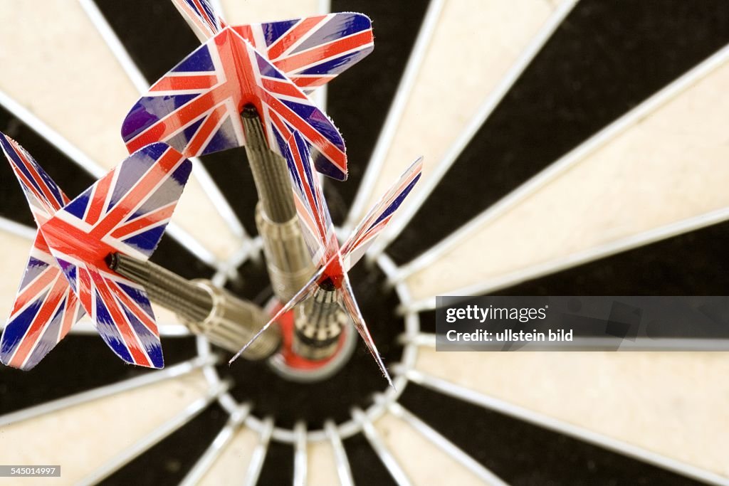 Dart arrows with Britsh national emblem sticking in the target of a dartboard.