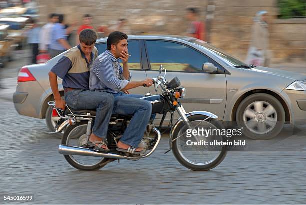 Turkey, Anatolia, Urfa, motorcyclist wearing sandales is driving without helmet and smoking a cigarette ,