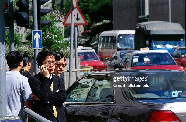 Junger Geschäftsmann mit Handy imStraßenverkehr- 04.1997 col