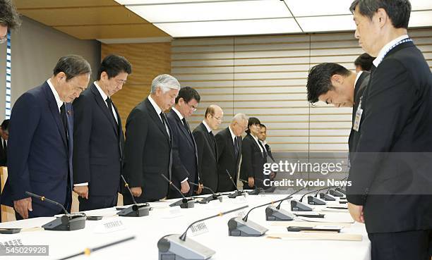 Members of Japanese Prime Minister Shinzo Abe's Cabinet bow their heads as they hold a moment of silence for the seven Japanese victims of a...