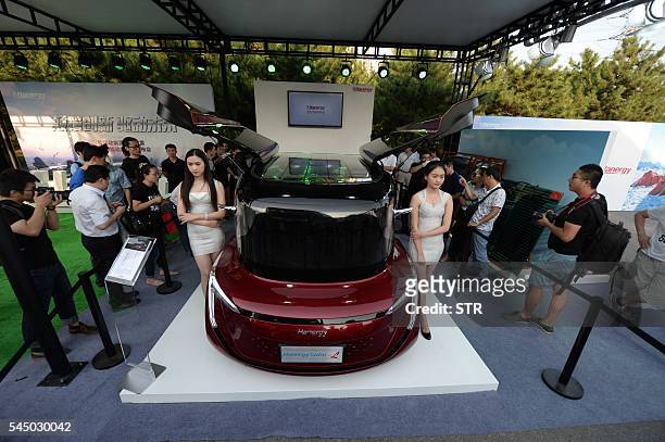 This photo taken on July 2, 2016 shows people looking at a Hanergy solar-powered car during a launch event in Beijing. Thin-film power giant Hanergy...