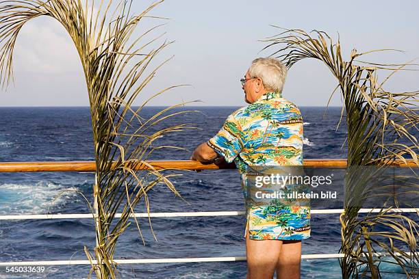 Cruise ship MS Astor in the Caribbean. Passenger leaning on the railing . Man wears an aloha shirt - only-editorial-use