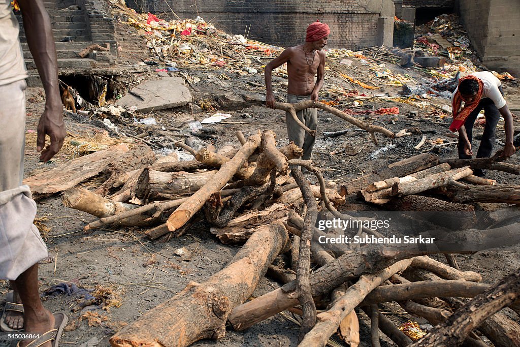People arrange logs of wood to cremate a corpse at...