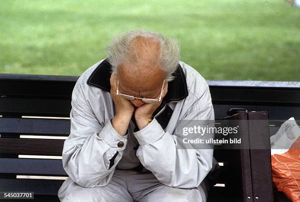 älterer Mann sitzt auf Parkbank undhat Kopf in die Hände gestützt- 1997