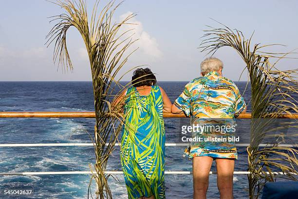 Cruise ship MS Astor in the Caribbean. Passenger leaning on the railing . Man wears an aloha shirt - only-editorial-use