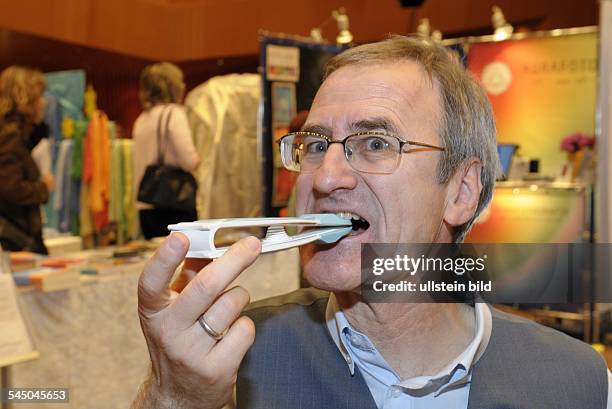 Germany - Saarland - Saarbruecken: Trade fair "Grenzenlos", man shows the new "Dento'Clip", a head and neck muscle trainer