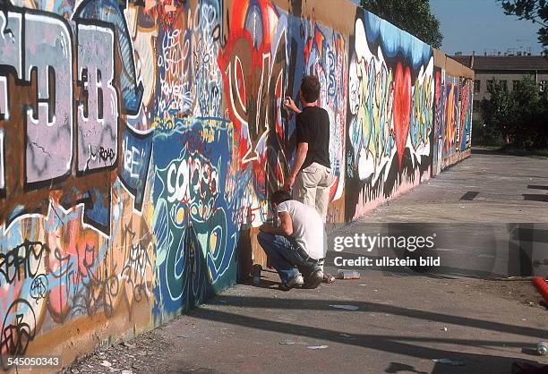 Zwei Jugendliche sprühen Graffitis auf einer Mauer- Juni 2001