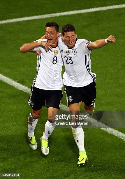 Mesut Oezil of Germany celebrates scoring the opening goal with his team mate Mario Gomez during the UEFA EURO 2016 quarter final match between...