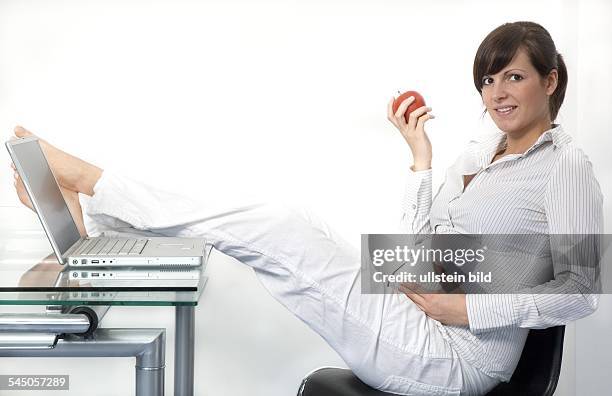 Schwangerschaft, schwangere junge Frau am Schreibtisch macht eine Pause und isst einen Apfel
