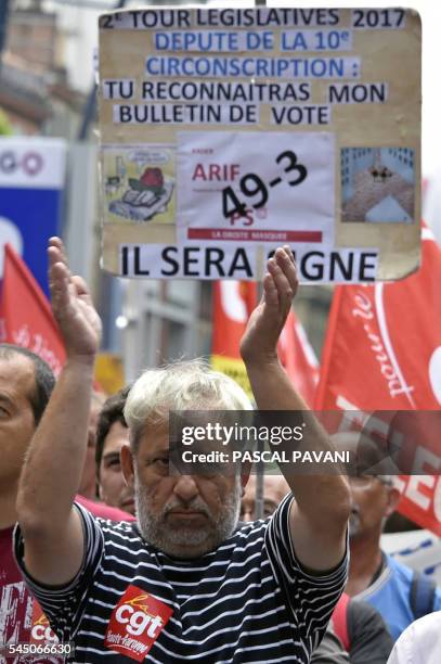 Man gestures as a person holds a cardboard reading 'legislative round 2017, deputy of 10th district, you will recognise my ballot, 49-3, it will be...