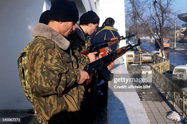 Jugendliche auf einem Balkon überprüfenihre Kalaschnikows.- 1996