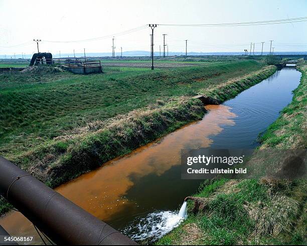 Rotbraun gefärbtes Abwasser wird ineinen Graben geleitetBei Bitterfeld 1993