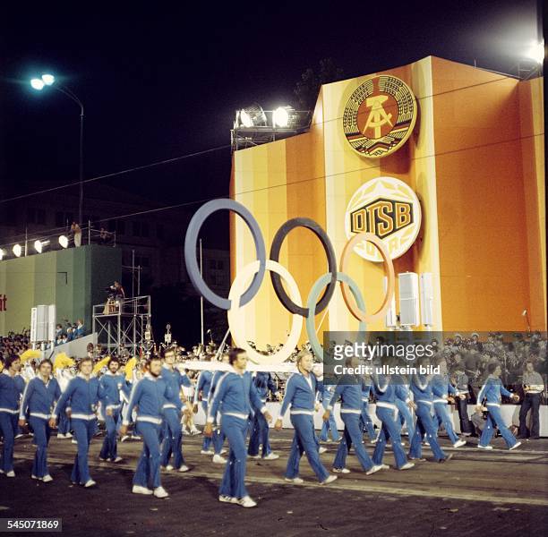 Festumzug: Sportler tragen die fünfOlympischen Ringe und die OlympischeFlagge an der Ehrentribüne vorbei- Juli 1977