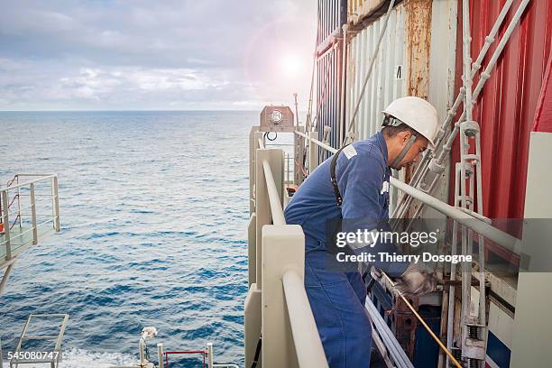 manual worker on container ship - adjusting blue tie stock-fotos und bilder