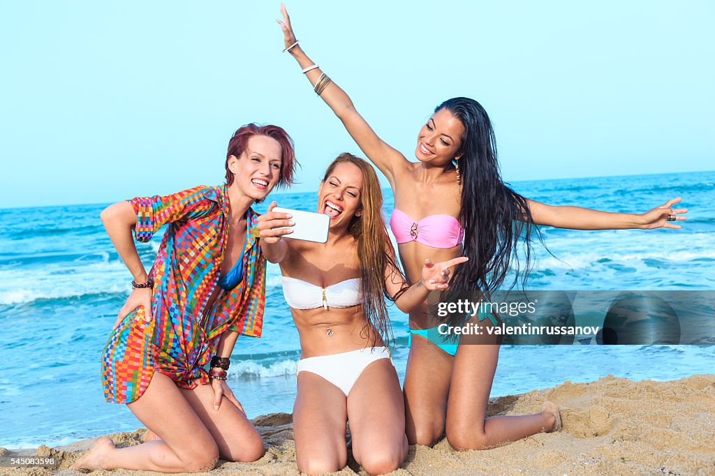 Young female friends making selfie on the beach