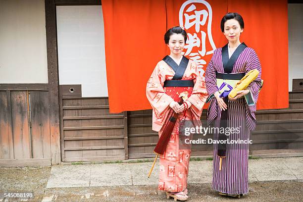 zwei frauen mit sonnenschirmen zu fuß auf einem alten straße, japan - edo period stock-fotos und bilder