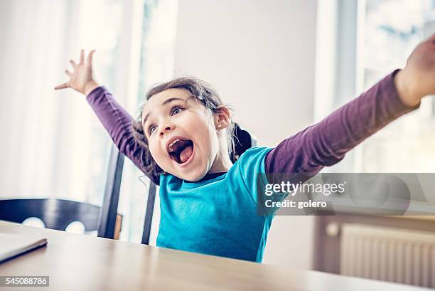 happy cute little girl cheering at desk - kid cheering stock pictures, royalty-free photos & images