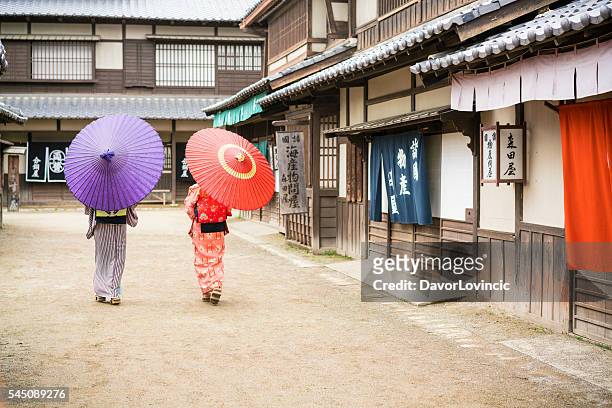 two women with umbrellas walking on an old street, japan - actor japan stock pictures, royalty-free photos & images