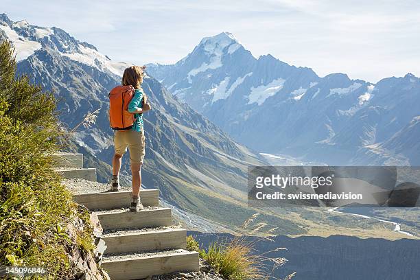 hiker stands on a mountain top and admires view - new zealand stock pictures, royalty-free photos & images