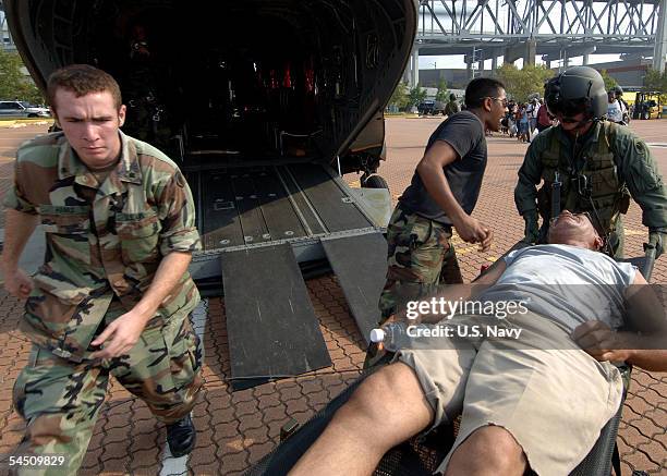 In this handout provided by the U.S. Navy, Army National Guard air crewmen and Air Force National Guard personnel load a Hurricane Katrina victim...