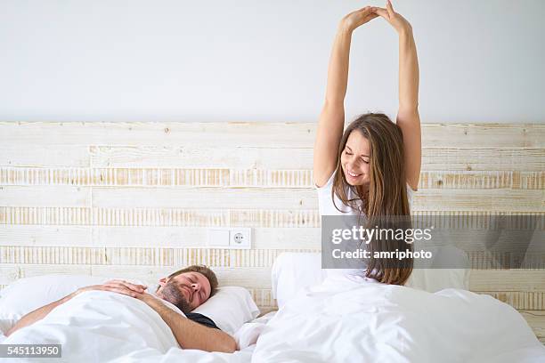 young couple in bed - woman stretching after waking up - jet lag 個照片及圖片檔