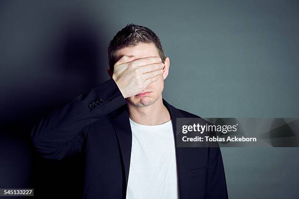 young male cover his eyes - augen zuhalten stock-fotos und bilder
