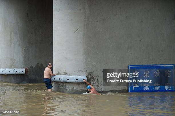 Swimmer tries to climb a pier of a bridge across Hanjiang River on July 04, 2016 in Hubei province, China. Heavy rains have caused flooding in...