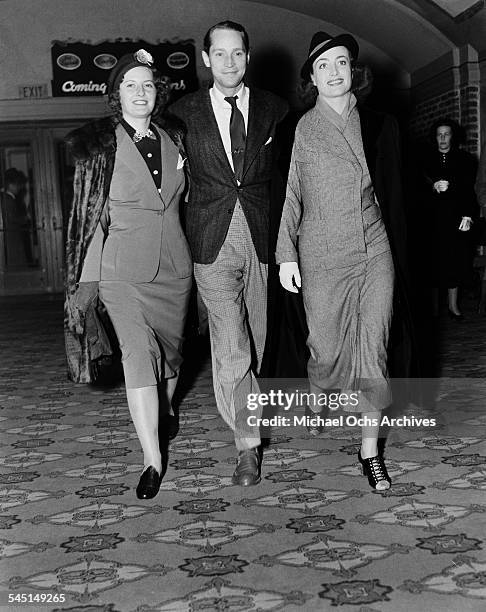 Actress Joan Crawford and husband Franchot Tone walks with actress Barbara Stanwyck to attend an event in Los Angeles, California.