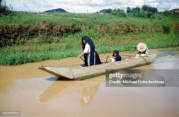 Two women and a man paddle a boat on the lake in Patzcuaro, Michoacan, Mexico.