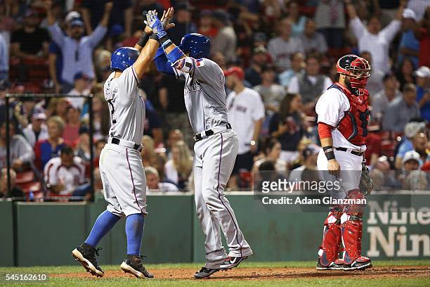 Robinson Chirinos high fives Rougned Odor of the Texas Rangers after hitting a three run home run in the ninth inning of the game against the Boston...