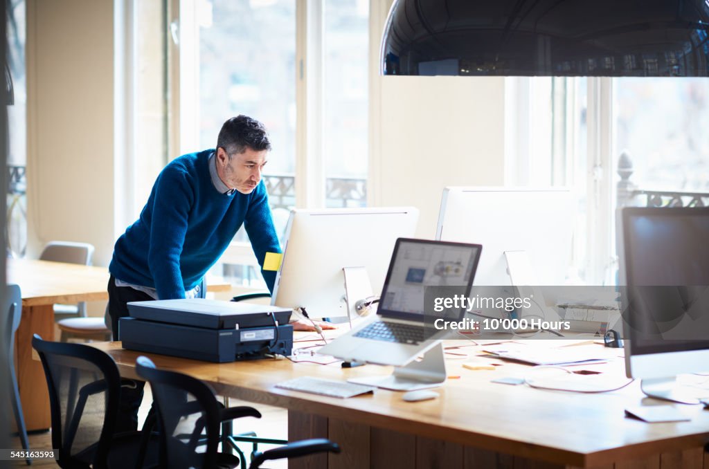 Businessman standing by desk working on a computer