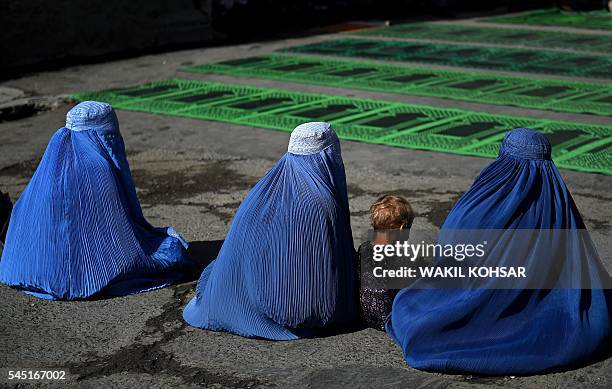 Afghan clad-burqa women beg for alms during prayers at the start of the Eid al-Fitr holiday which marks the end of Ramadan, at the Shah-e Do...