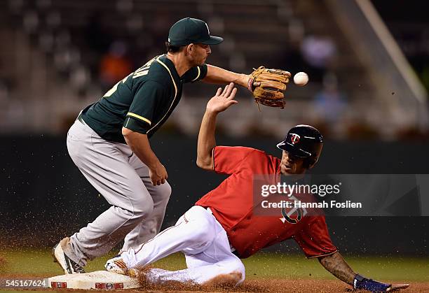 Byron Buxton of the Minnesota Twins slides safely into third base as Danny Valencia of the Oakland Athletics fields the ball during the sixth inning...