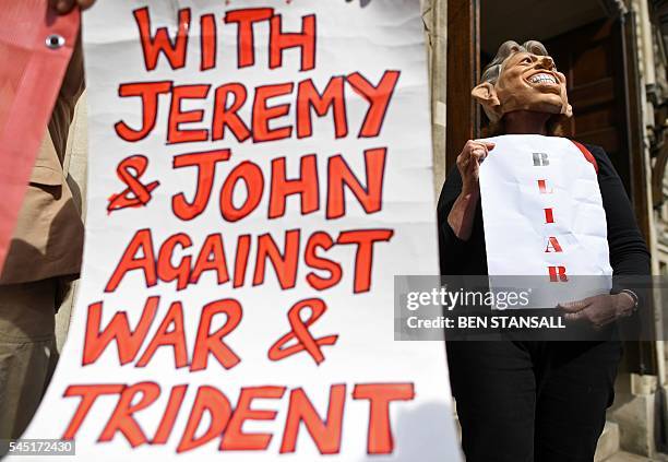 Demonstrator wearing a mask depicting former British Prime Minister Tony Blair protests outside QEII Centre in London on July 6 as they wait to hear...