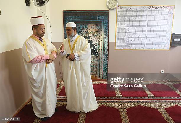 Two imams chat next to a schedule of Ramadan fasts at the House of Wisdom mosque and community center in Moabit district during celebrations marking...