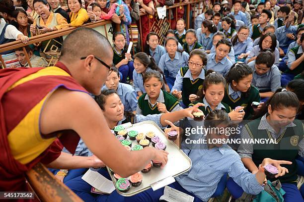 An exiled Tibetan monk distributes cupcakes to school children to mark the Dalai Lama's 81st birthday in McLeod Ganj on July 6, 2016. / AFP / Lobsang...