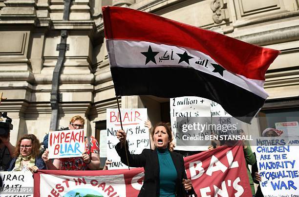 An Iraqi woman waves a 2004-2008 version of the Iraq national flag as she stands with demonstrators protesting outside QEII Centre in London on July...