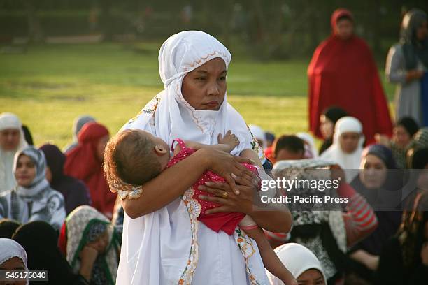 Mother carrying her child while waiting for the morning prayers to start at the Quirino Grandstand in Manila. Filipino Muslims from nearby cities...