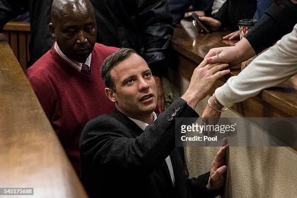 Olympic athlete Oscar Pistorius holds the hand of a relative after sentencing at the High Court on July 6, 2016 at the High Court in Pretoria, South...