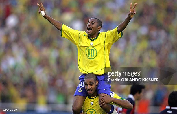 Brazilian striker Robinho is carried by forward Adriano celebrating Adriano's third goal -the fifth for Brazil- against Chile at the end of their...