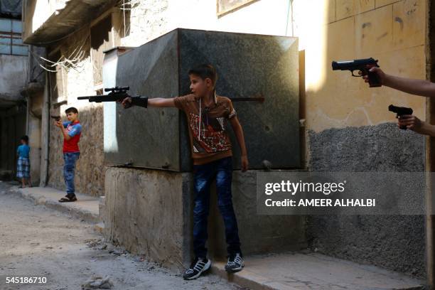 Syrian children play on a street with plastic toy guns in a rebel-held district of the northern city of Aleppo on July 6, 2016 during celebrations...