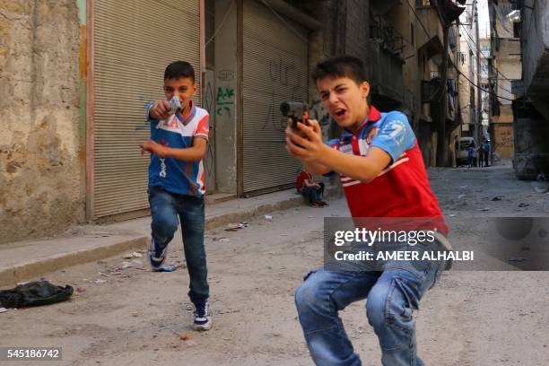 Syrian children play on a street with plastic toy guns in a rebel-held district of the northern city of Aleppo on July 6, 2016 during celebrations...