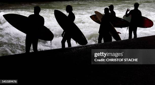 Surfers wait near the water of the so-called Eisbach canal, a popular site for surfers in the English Garden in Munich, southern Germany, on July 6,...