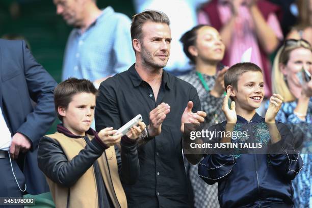 Former England footballer David Beckham and his sons Cruz and Romeo cheer Switzerland's Roger Federer's victory on centre court after he beat...