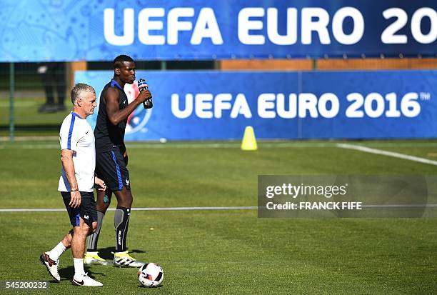 France's coach Didier Deschamps walks along side France's midfielder Paul Pogba during a training session in the southern French city of Marseille on...