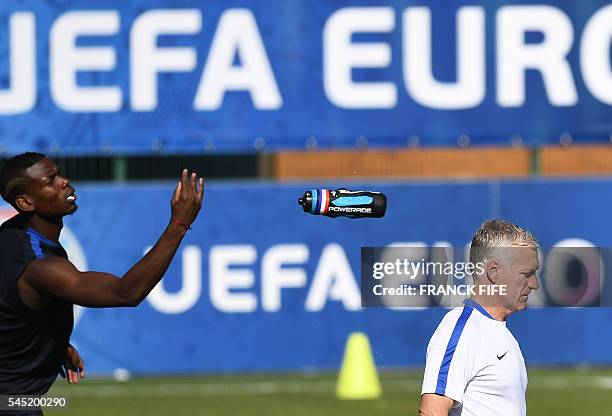 France's midfielder Paul Pogba throws his water battle past France's coach Didier Deschamps during a training session in the southern French city of...