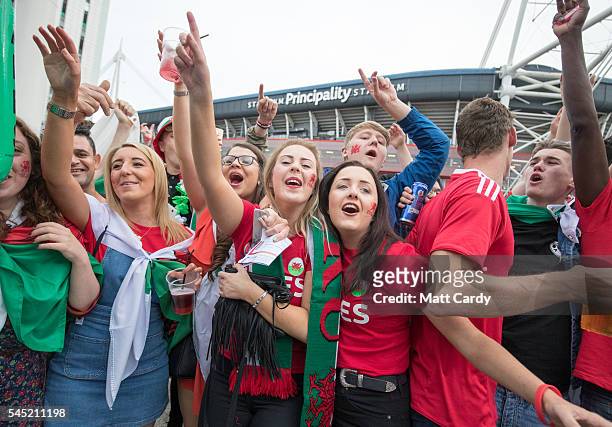 Welsh football fans cheer as they gather outside the Principality Stadium which is showing the Wales v Portugal game on a giant screen on July 6,...